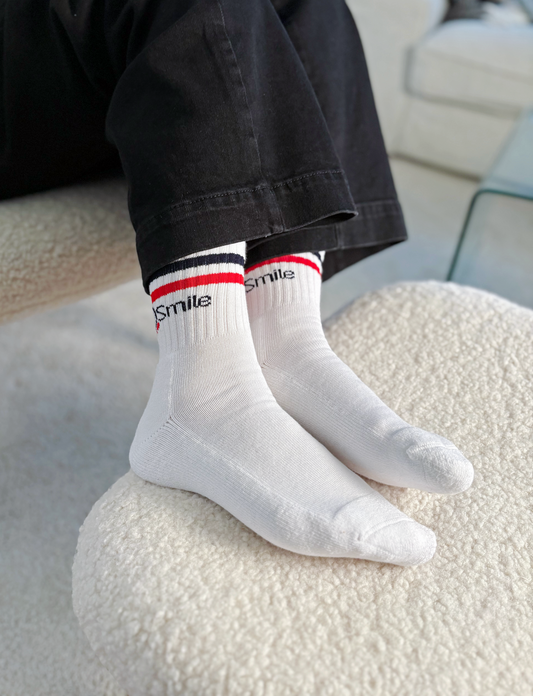 Vit bomullstrumpa med Operation Smile:s logga på skaftet